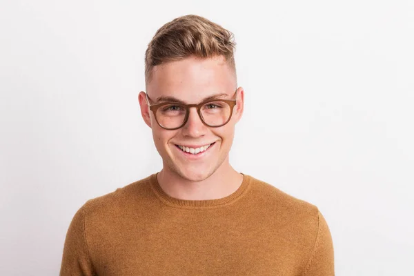 A confident young man in a studio, wearing glasses. — Stock Photo, Image