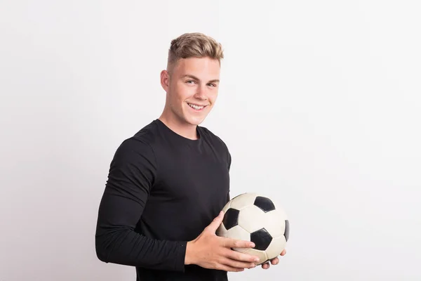 Porträt eines jungen Mannes mit Fußballball in einem Studio. Kopierraum. — Stockfoto