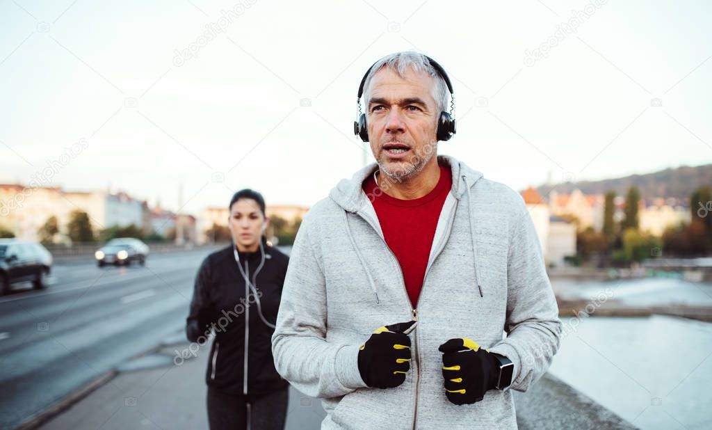 A fit couple with headphones running outdoors on the bridge in Prague city.