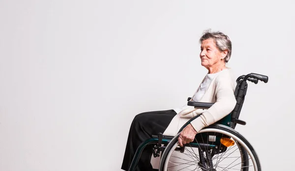 Studio tekerlekli sandalye ile üst düzey bir kadın portresi. — Stok fotoğraf