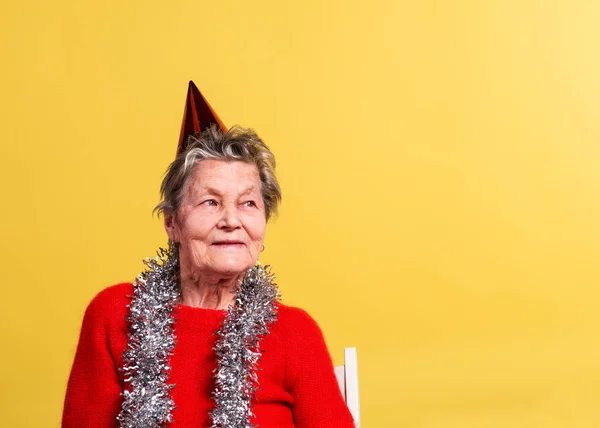 Porträt einer älteren Frau im Atelier auf gelbem Hintergrund. Parteikonzept. — Stockfoto