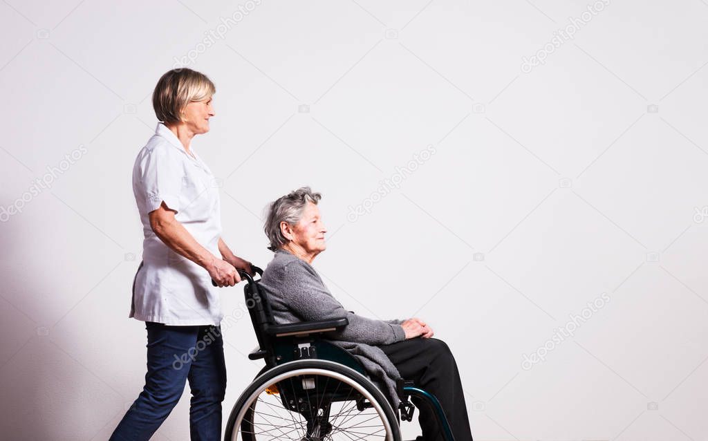 Studio portrait of a senior woman in wheelchair and a nurse.