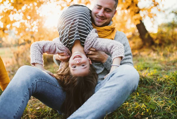Um jovem pai se divertindo com uma pequena filha na natureza do outono . — Fotografia de Stock