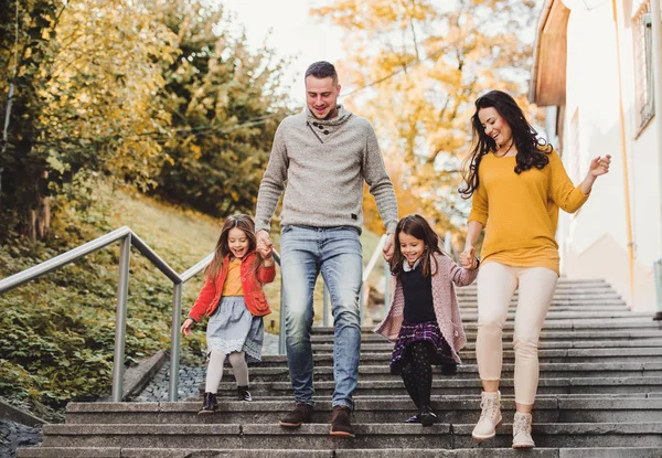 Mladá rodina s dětmi, chůzi po schodech venku ve městě na podzim. — Stock fotografie