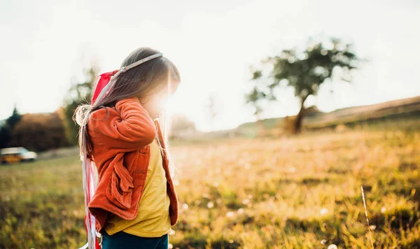 Una bambina che gioca con un aquilone a mano arcobaleno in autunno natura al tramonto . — Foto Stock