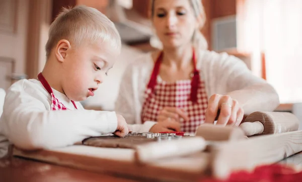 Ein behinderter Junge mit Down-Syndrom und seine Mutter backen im Haus. — Stockfoto