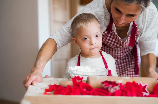 Az anyjával, beltéri Sütés boldog fogyatékos down-szindróma child. — Stock Fotó