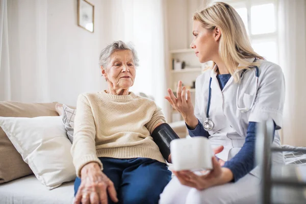 Zdravotníka, měření krevního tlaku doma starší ženy. — Stock fotografie