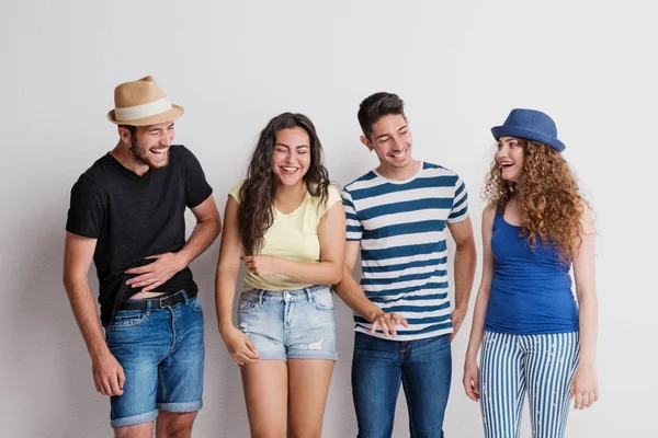 Ritratto di giovane gioioso gruppo di amici con cappelli in piedi in uno studio, ridendo . — Foto Stock