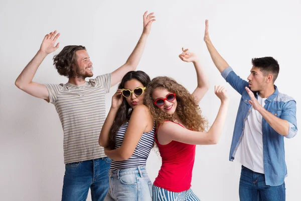 Retrato de jóvenes amigos alegres con gafas de sol bailando en un estudio . —  Fotos de Stock