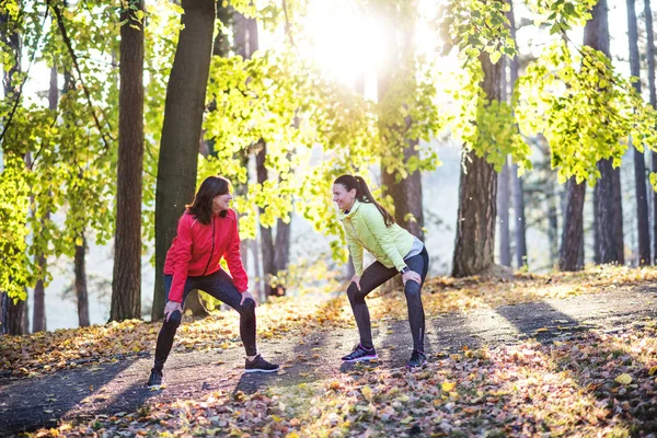 Két női futók nyújtás kint az erdő őszi természet. — Stock Fotó