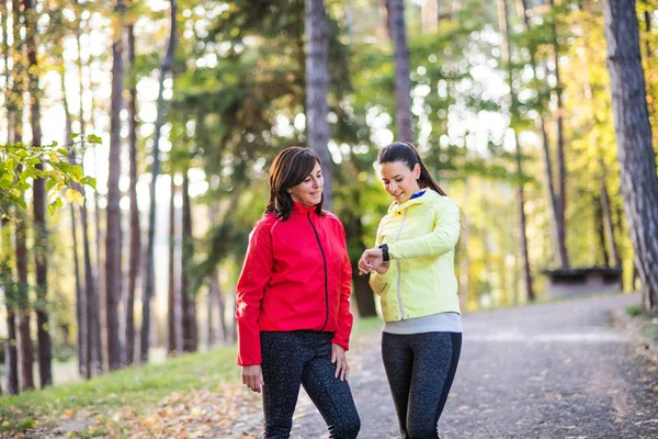 Läuferinnen mit Smartwatch draußen im Wald in der Natur und überprüfen die Zeit. — Stockfoto