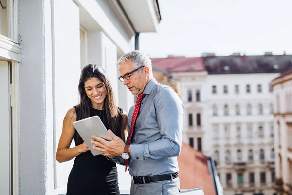 Partenaires d'affaires homme et femme avec tablette debout sur une terrasse en ville, parler . — Photo