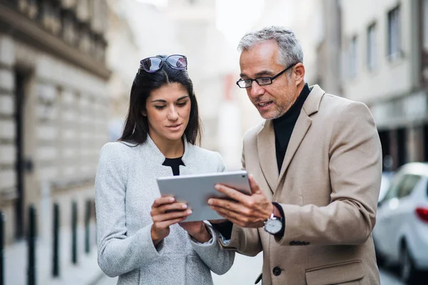 Geschäftspartner mit Tablet stehen draußen in der Stadt und unterhalten sich. — Stockfoto