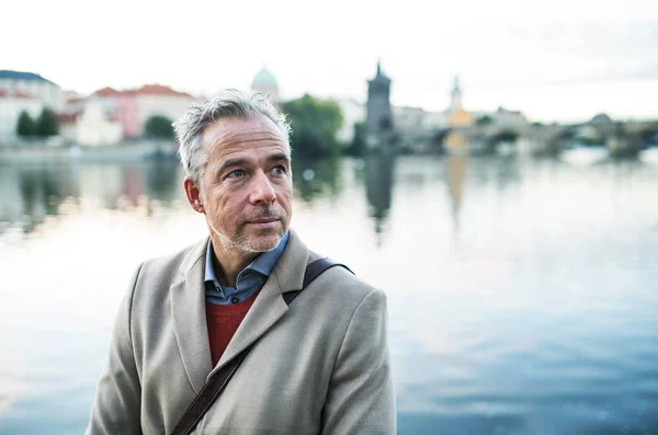 Rijpe zakenman permanent door rivier Vltava in Praag stad. Kopiëren van ruimte. — Stockfoto