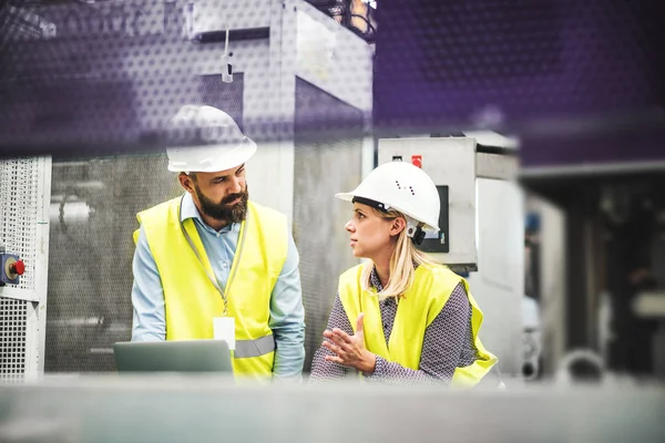 Ett porträtt av ingenjör industriell-man och kvinna med laptop i en fabrik, arbetar. — Stockfoto