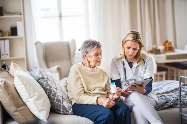 Pielęgniarka środowiskowa wyjaśniając starszy kobieta jak przyjmować tabletki. — Zdjęcie stockowe