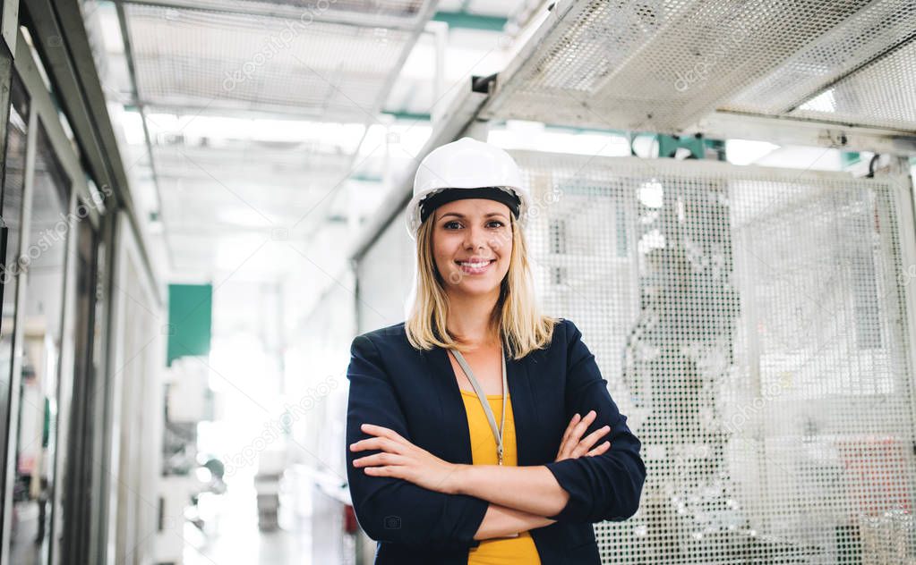 A portrait of an industrial woman engineer standing in a factory.