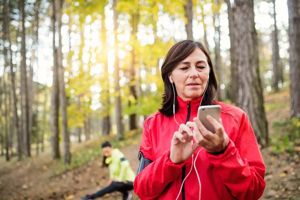 Две бегунки со смартфоном отдыхают в лесу осенью на природе . — стоковое фото