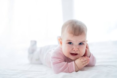 Kapalı yatakta yatarken mutsuz bebek kız portresi.