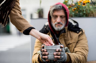Para için şehirde oturan evsiz dilenci adam tanınmaz halde bir kadın.