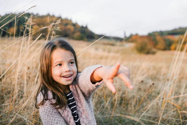 Ένα μικρό κορίτσι, στέκεται το φθινόπωρο φύση, δείχνει δάχτυλο σε κάτι. — Φωτογραφία Αρχείου