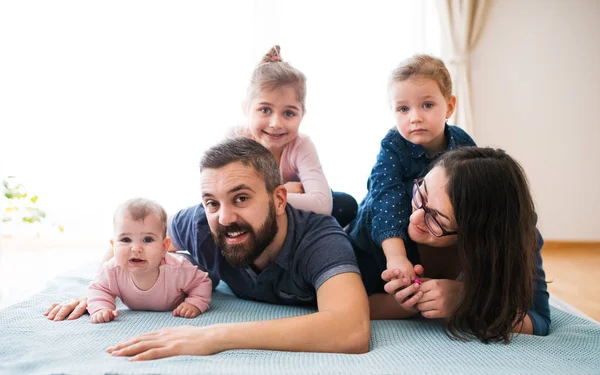 Egy fiatal család kis gyerekekkel, feküdt a padlón beltéri portré. — Stock Fotó