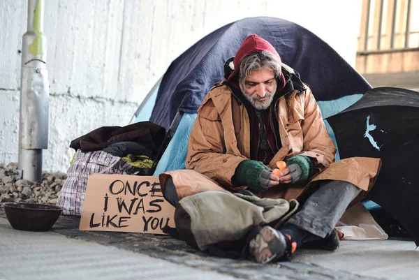 Hombre mendigo sin hogar sentado al aire libre en la ciudad pidiendo una donación de dinero . — Foto de Stock