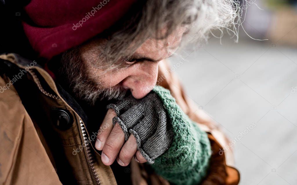 A close-up view of homeless beggar man standing outdoors in city. A close-up view of homeless beggar man standing outdoors in city.