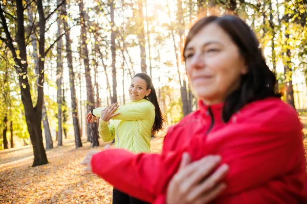 Açık havada sonbahar doğada ormandaki uzanan iki kadın koşucu. — Stok fotoğraf