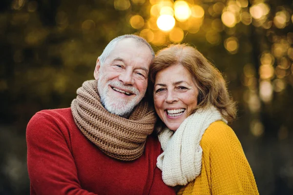 A senior couple standing in an autumn nature at sunset, hugging. — Stock Photo, Image
