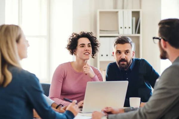 Grupo de jóvenes empresarios con portátil trabajando juntos en una oficina moderna . — Foto de Stock