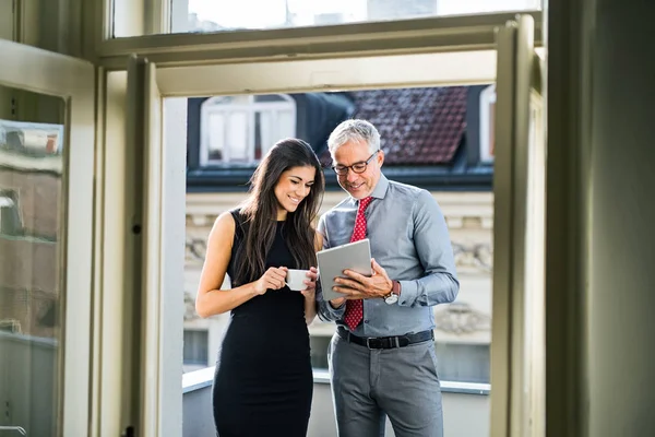 Hombre y mujer socios de negocios con la tableta de pie en una terraza en la ciudad, hablando . — Foto de Stock