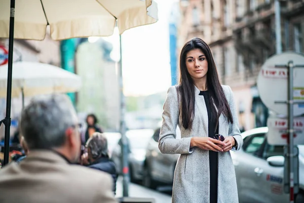An attractive businesswoman standing outdoors on a sidewalk in a city. — Stock Photo, Image