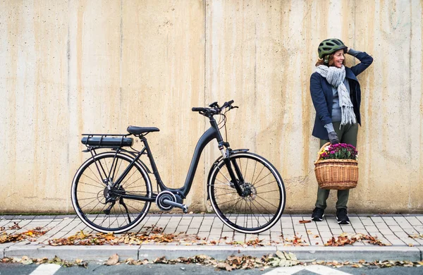 Electrobike 自転車にもたれて、町で屋外で立ってアクティブ シニア女性. — ストック写真
