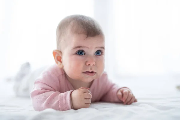 Portrét baby Girl ležící na posteli uvnitř. — Stock fotografie