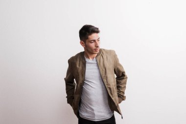 Kendine güvenen genç İspanyol biri bir stüdyoda eller cebe.