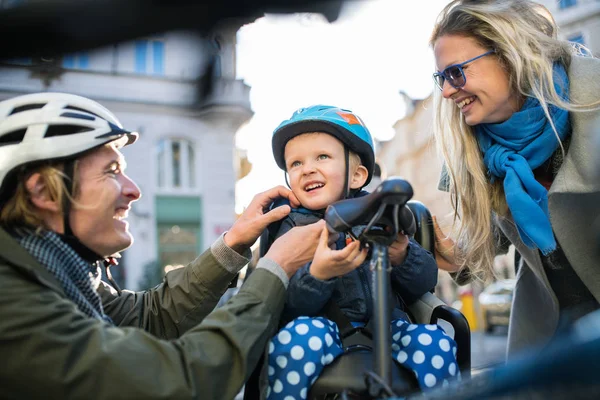 Ein kleiner Junge mit Helm und jungen Eltern im Freien in der Stadt. — Stockfoto