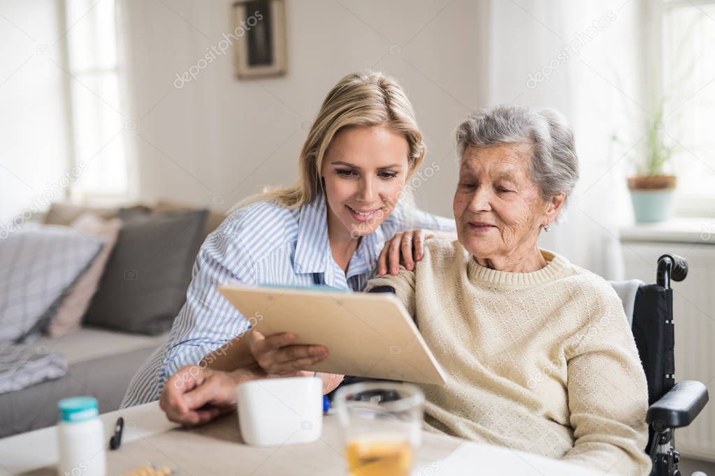 A health visitor measuring a blood pressure of a senior woman at home.