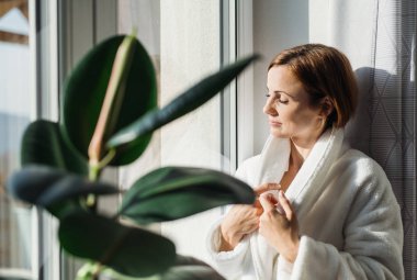 Banyo bornoz ve kapalı gözleri kapalı duran bir pencere tarafından sabah, Genç bir kadın meditasyon. Kopya alanı.