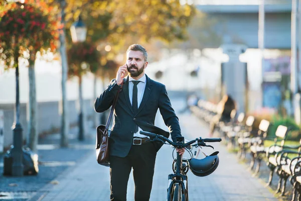 Empresario viajero con bicicleta a pie a casa desde el trabajo en la ciudad, utilizando el teléfono inteligente . — Foto de Stock