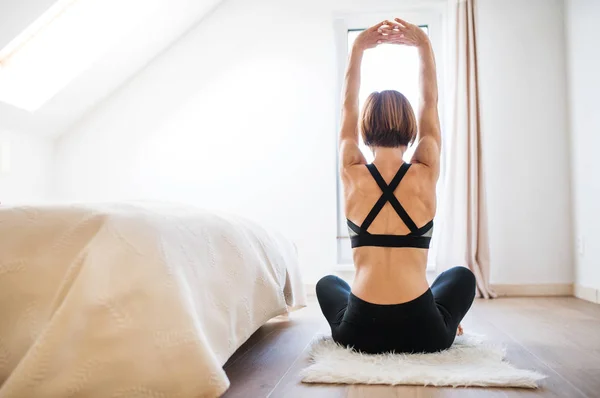 Eine Rückansicht einer jungen Frau, die in einem Schlafzimmer Sport treibt. Kopierraum. — Stockfoto