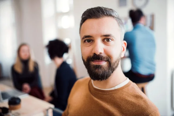 Portrait d'un jeune homme d'affaires avec des collègues dans un bureau moderne . — Photo