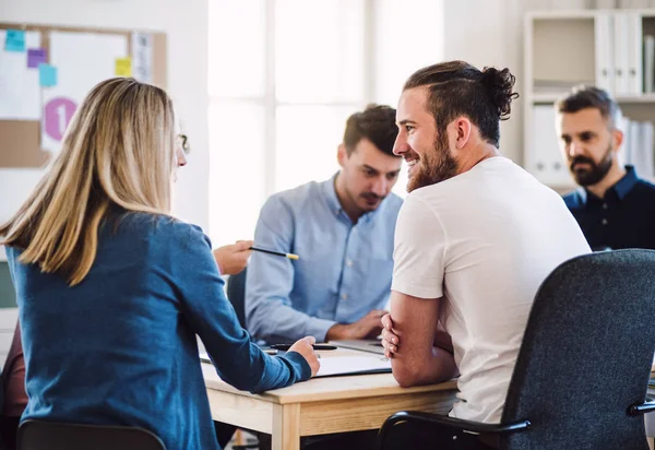 Group of young businesspeople sitting around table in a modern office, having meeting. — Stock Photo, Image