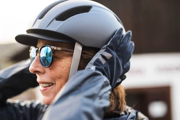 Primo piano della donna anziana attiva in piedi all'aperto, indossando il casco da bicicletta . — Foto Stock