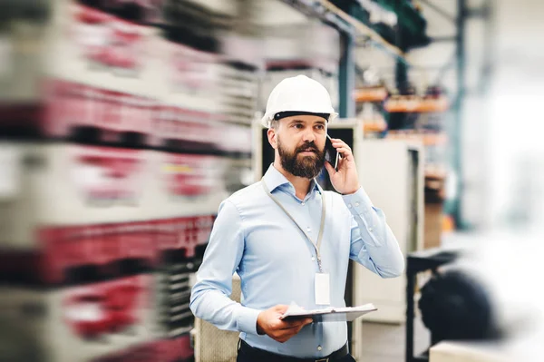 Un retrato de un ingeniero industrial con smartphone en una fábrica, trabajando . — Foto de Stock