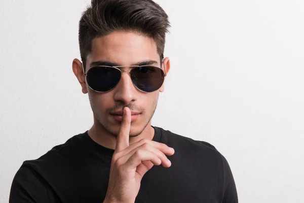 Un joven hispano confiado con gafas de sol y camiseta negra en un estudio . —  Fotos de Stock