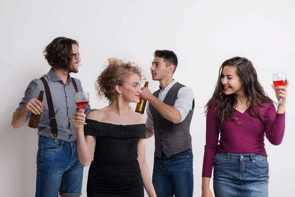 Portret van jonge groep vrienden permanent in een studio, flessen en glazen. — Stockfoto