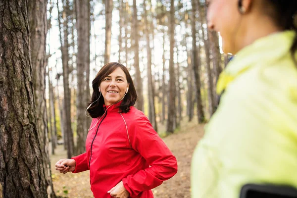 Женщины бегуны с наушниками бегают на природе в лесу . — стоковое фото