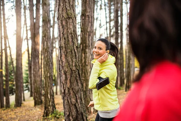 Coureurs féminins avec écouteurs et smartphones jogging en plein air dans la forêt . — Photo